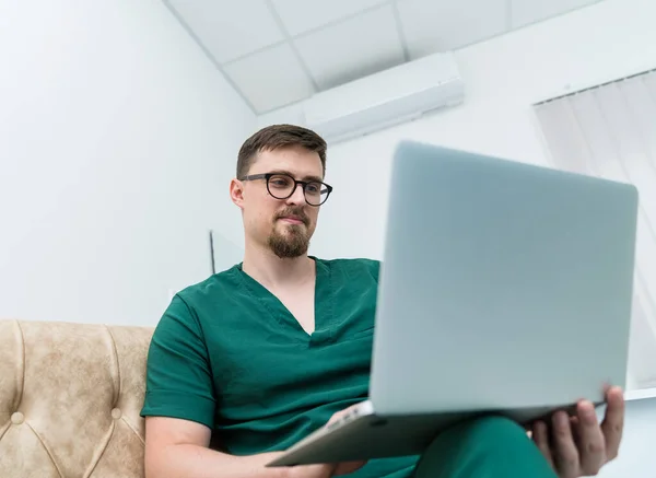 Professional medical specialist with computer. Handsome young doctor working with laptop.