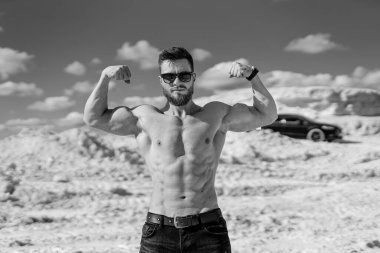 Muscular bare torso. Man with muscular body posing outdoors shirtless.