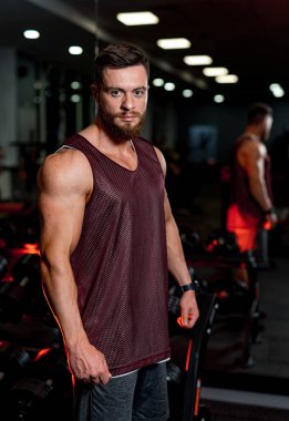 Spor salonundaki güçlü adam ayakta duruyor. Genç erkek fitness model vücut geliştirici.