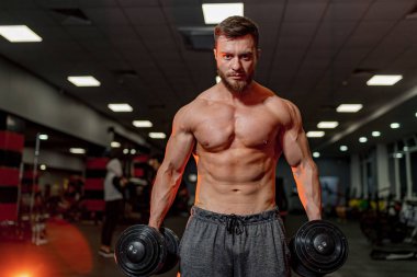 Spor salonunda çalışan kaslı vücutlu bir erkek. Güçlü üstsüz adam vücudunu çalıştırıyor..