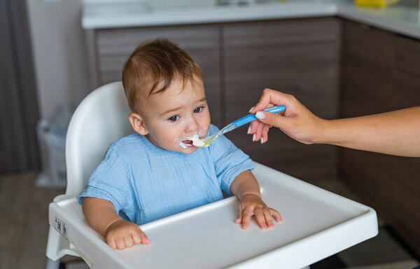 Small cute kid eating from spoon. Young happy child portrait having breakfest.