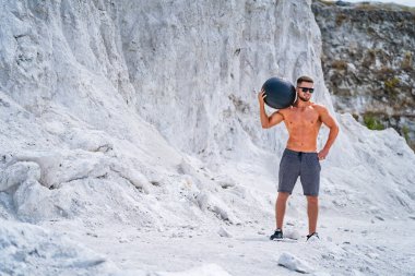 Açık havada üstsüz antrenman yapan kaslı yakışıklı bir adam. Sportif vücudu olan güçlü bir adam..