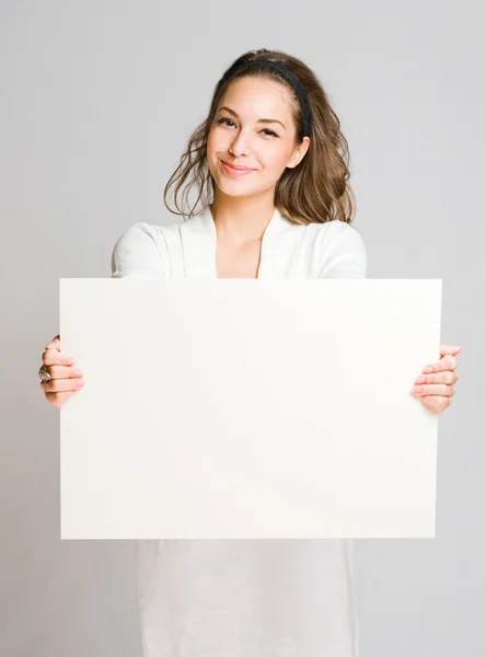 Chherful joven morena con pancarta en blanco . — Foto de Stock