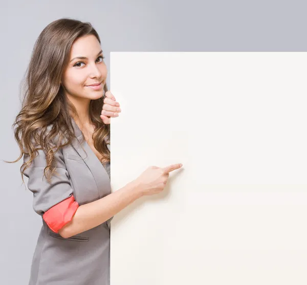 Young brunette pointing at empty billboard. Royalty Free Stock Images