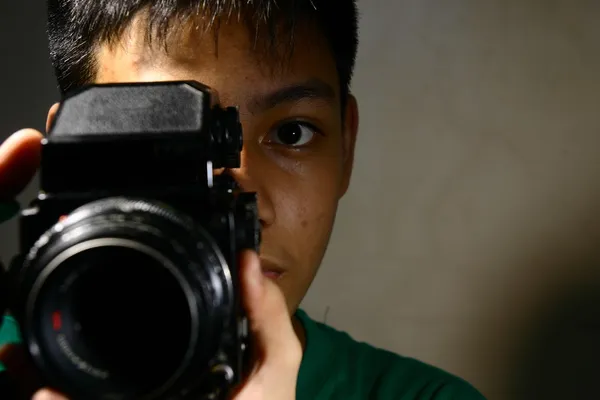 Pessoa ou adolescente olhando através de uma câmera de filme de médio formato — Fotografia de Stock