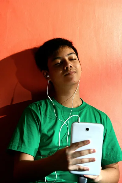 Junge asiatische Teenager hören Musik auf einem Tablet in einem Wohnzimmer — Stockfoto