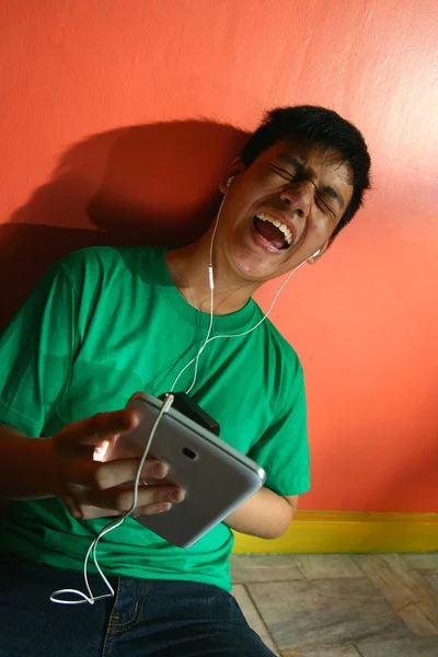 Jovem asiático adolescente ouvindo música em um tablet em uma sala de estar — Fotografia de Stock