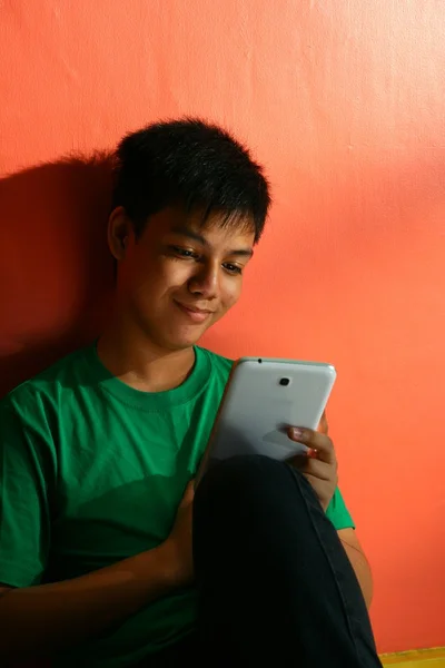 Young asian teen with a tablet in a living room — Stock Photo, Image