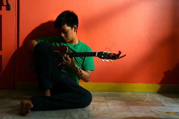 Fiatal ázsiai tini gitározni a nappaliban — Stock Fotó