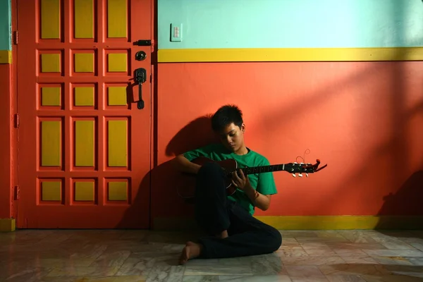 Jovem asiático adolescente tocando guitarra em uma sala de estar — Fotografia de Stock