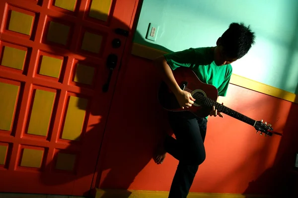 Ung asiatisk teen spela gitarr i ett vardagsrum — Stockfoto