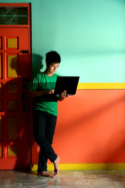 Young asian teen with a laptop computer in a living room — Stock Photo, Image
