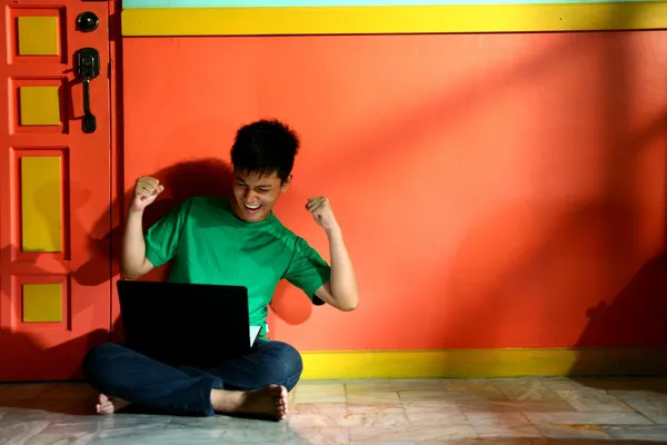 Young asian teen with a laptop computer in a living room — Stock Photo, Image