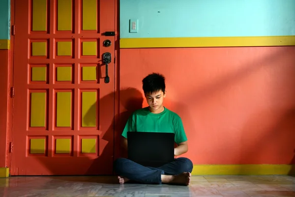 Young asian teen with a laptop computer in a living room — Stock Photo, Image