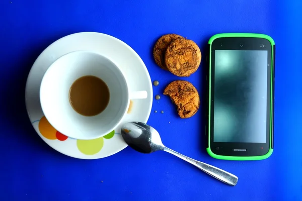 Café terminado en una taza de cerámica, galletas y un teléfono celular — Foto de Stock