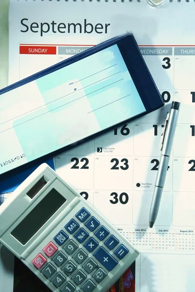 Calendário, livro de cheques, calculadora, dinheiro e uma esferográfica — Fotografia de Stock