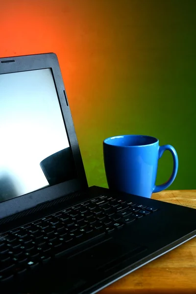 Laptop und ein blauer Kaffeebecher — Stockfoto
