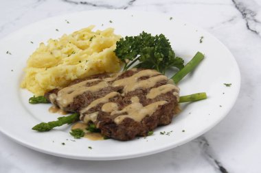 Photo of freshly cooked beef steak with mashed potato and gravy.