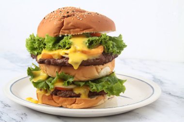 Peynirli ve sebzeli yeni yapılmış büyük bir hamburgerin fotoğrafı..