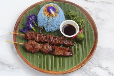 Mavi pirinç ve soya sosuyla servis edilen taze ızgara domuz eti..