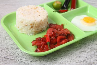 Photo of freshly cooked Filipino food called pork tocilog or cured pork served with fried rice and egg.