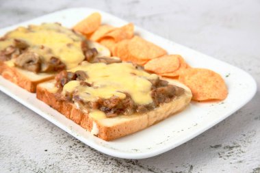 Photo of freshly made tuna and cheese melt sandwich served with potato chips
