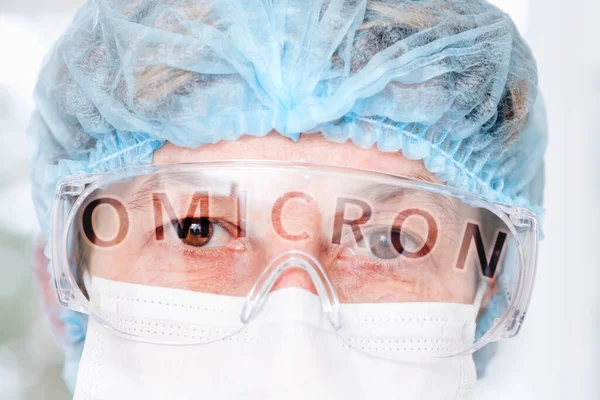 Ojos de médico a través de gafas y palabra omicrón en reflexión — Foto de Stock