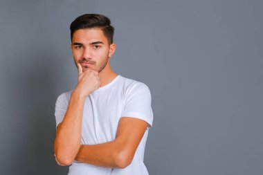 Dalgın yakışıklı adam tıraşsız çeneye dokunuyor.