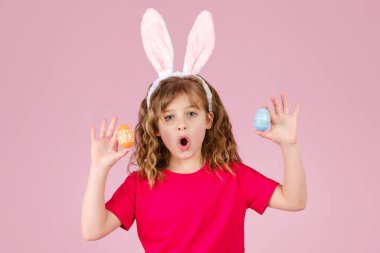 Paskalya tavşanı kulaklıklı kız renkli yumurtalarla el ele tutuşuyor.