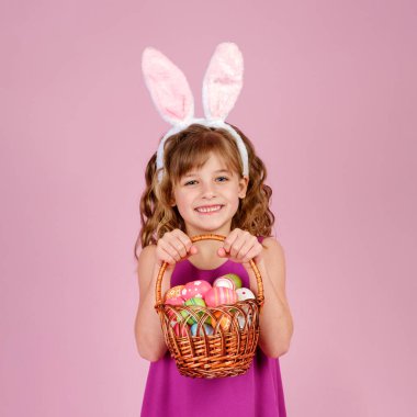 Paskalya yumurtalarını pembe stüdyoda tutan neşeli çocuk.