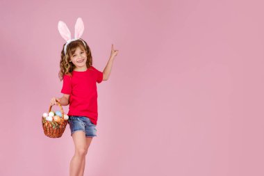 Paskalya yumurtalarını pembe stüdyoda tutan neşeli çocuk.