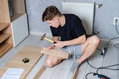 Odasında ahşap mobilyalarla çalışan genç adam.