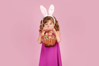 Paskalya yumurtalarını pembe stüdyoda tutan neşeli çocuk.