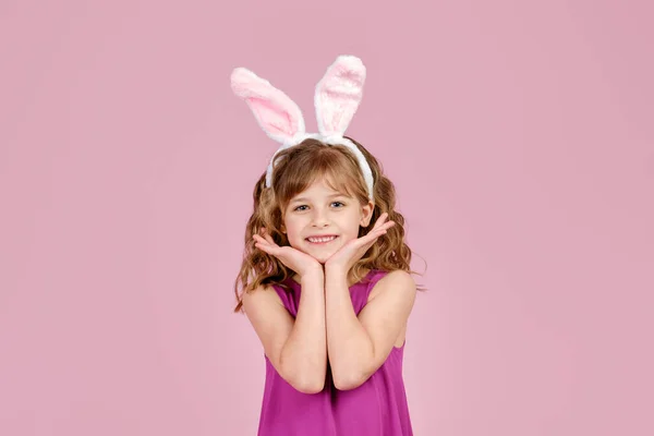 Söt liten flicka med kaninöron vidrör ansikte och ler i studio — Stockfoto