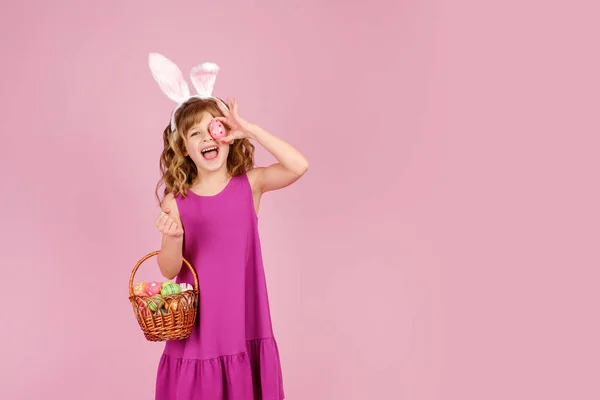Content kid with basket covering eye with Easter egg — Stock Photo, Image