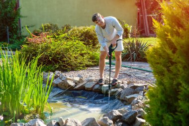 Adam çamurdan ve çamurdan yüksek basınçlı çamaşır makinesiyle havuzun dibini temizliyor..