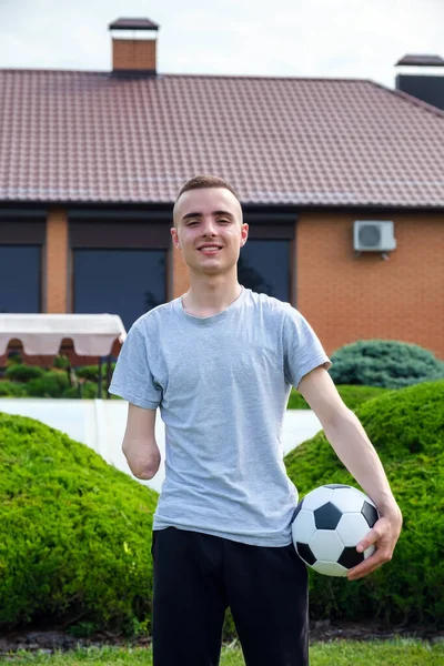 Uomo con braccio amputato tiene piede sul pallone da calcio mentre in piedi sul prato — Foto Stock