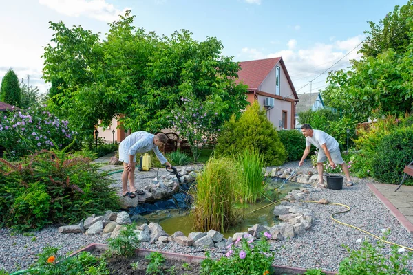 Father and son cleaning artificial pond — Stock Photo, Image
