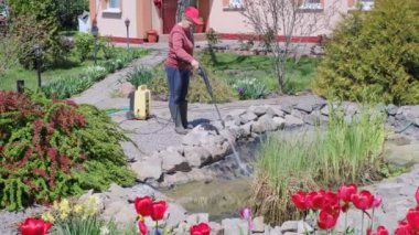  Kadın, yüksek basınçlı çamaşır makinesiyle havuzun dibini ve alüvyonu temizliyor. 