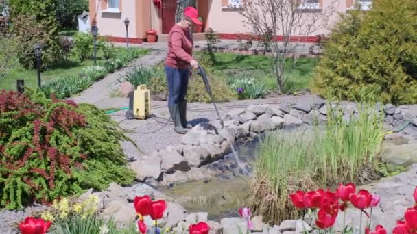 妇女用高压洗衣机清洗花园池塘底部的泥土和淤泥 — 图库视频影像