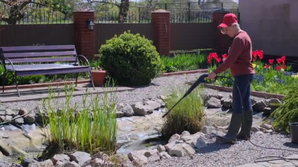 Woman cleans garden pond bottom from dirt and silt with high-pressure washer — Vídeo de Stock