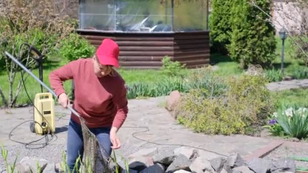 Woman with a landing net catches fish before cleaning a decorative garden pond — Vídeo de Stock