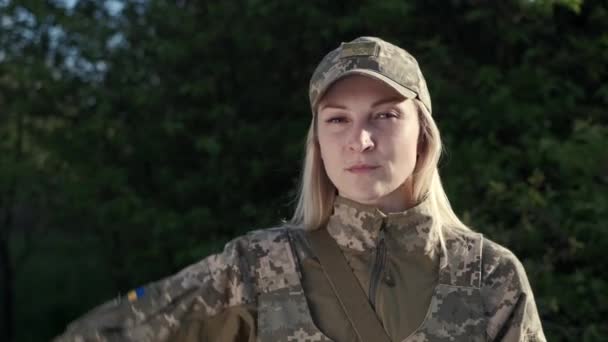 Жінка-солдат у камуфляжній формі сахається і дивиться на камеру — стокове відео