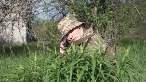 Ukrainska kvinnliga soldat beväpnad med en attack gevär som ligger i gräs och siktar — Stockvideo