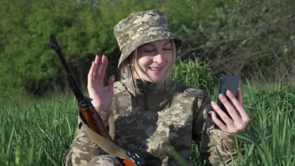 Une femme soldat avec un fusil d'assaut communique avec quelqu'un par appel vidéo — Video