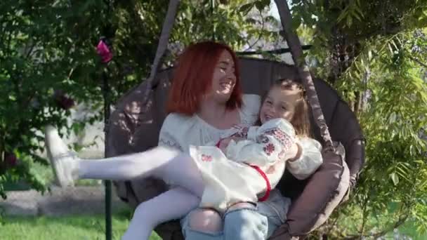 Sonriente y juguetona madre e hija se divierten sentados en silla colgante — Vídeo de stock