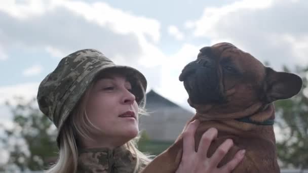 Mujer soldado sostiene y abraza a su bulldog francés — Vídeo de stock