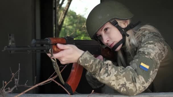 Primo piano donna in uniforme in zona di conflitto armato mira con un fucile d'assalto — Video Stock
