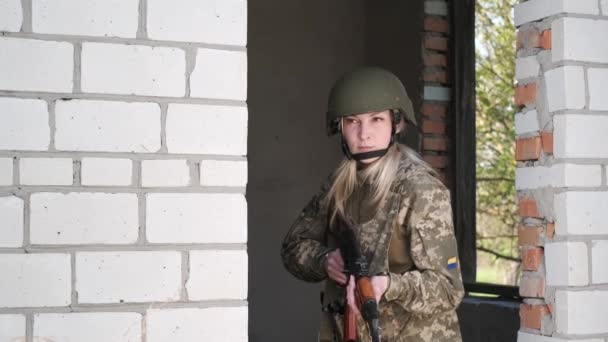 武力紛争地域の制服を着た女性は戸口からのアサルトライフルを目指しています — ストック動画