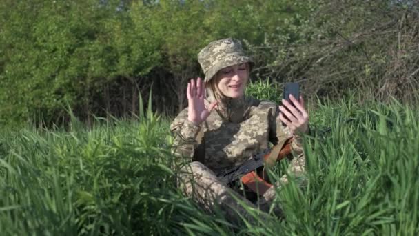 Une femme soldat avec un fusil d'assaut communique avec quelqu'un par appel vidéo — Video